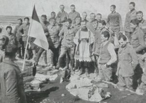 Żołnierze I Brygady Legionów Polskich stoją przy stole świątecznym. W centralnej części fotografii ksiądz.